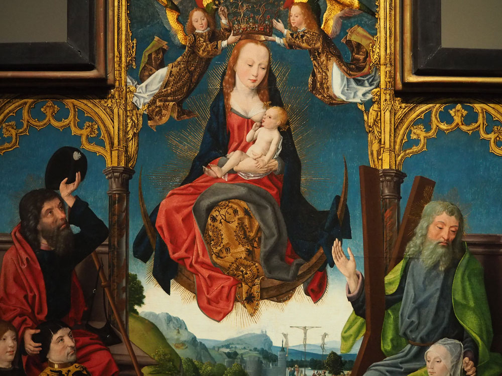 La Vierge Marie assise sur la Lune en portant son enfant dans les bras. Sur la droite, en contrebas, un homme est représenté avec une croix en bois en X faisant sa hauteur.
